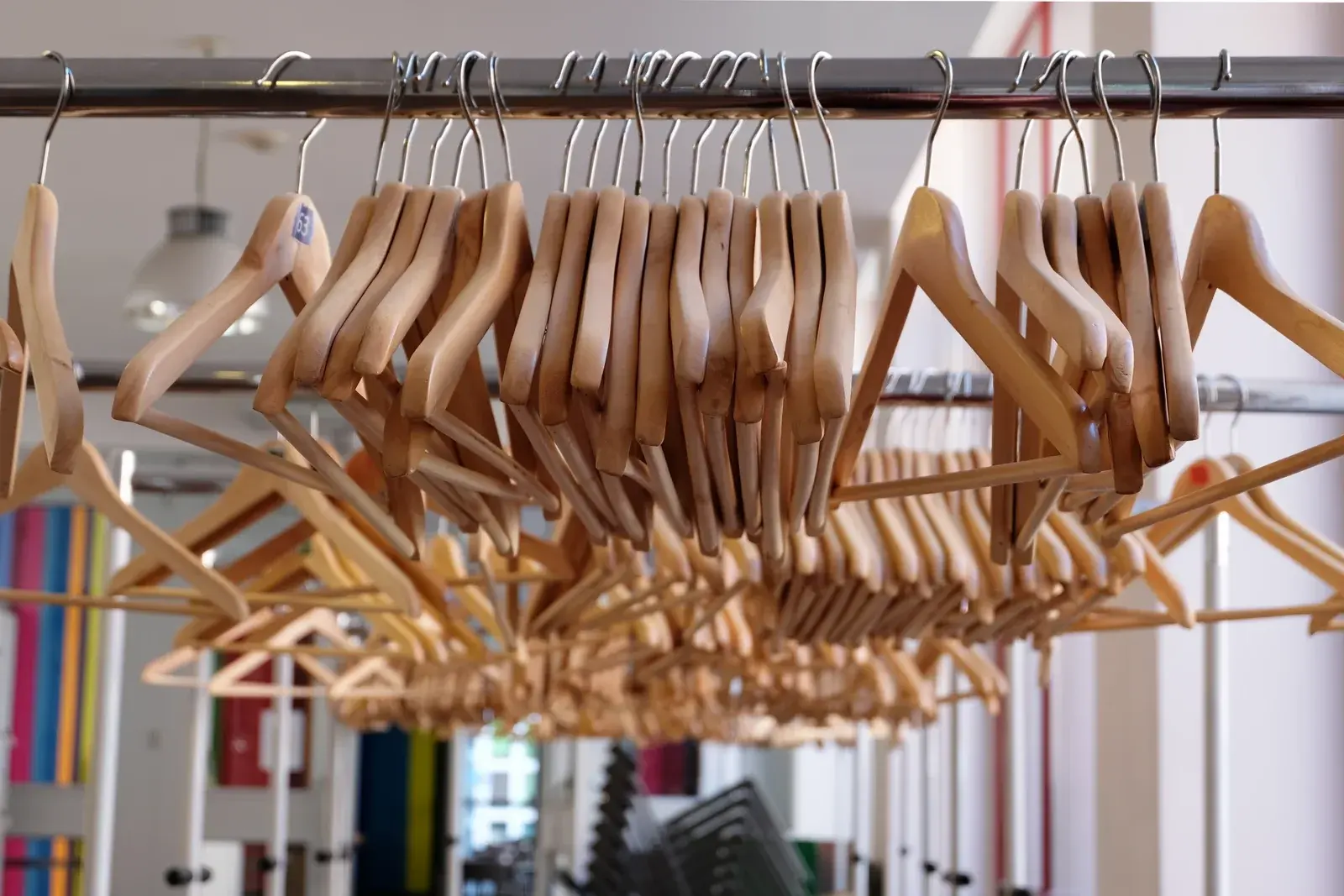 Rows of empty wooden clothes hangers on a chrome rail in a bright shop