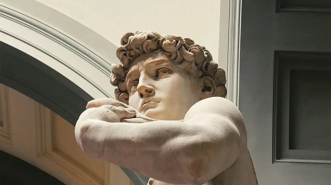 Michelangelo's David seen from below in a gallery under a vaulted ceiling
