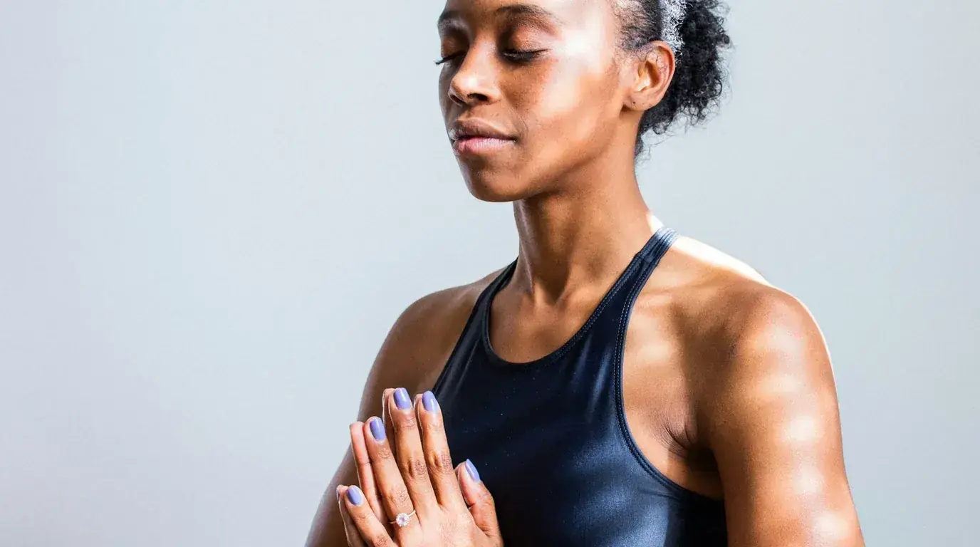 A woman in a navy vest standing with her hands pressed together at her chest