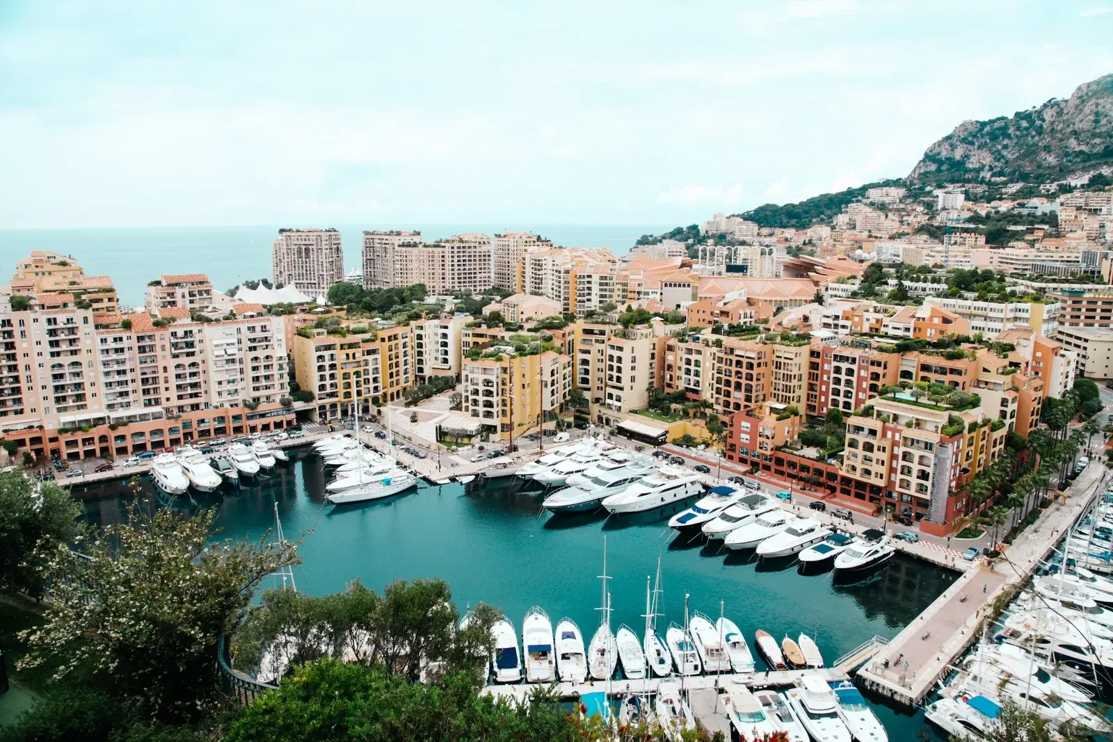 Rows of white motor yachts in the marina at Fontvieille, Monaco, ringed by ochre apartment blocks