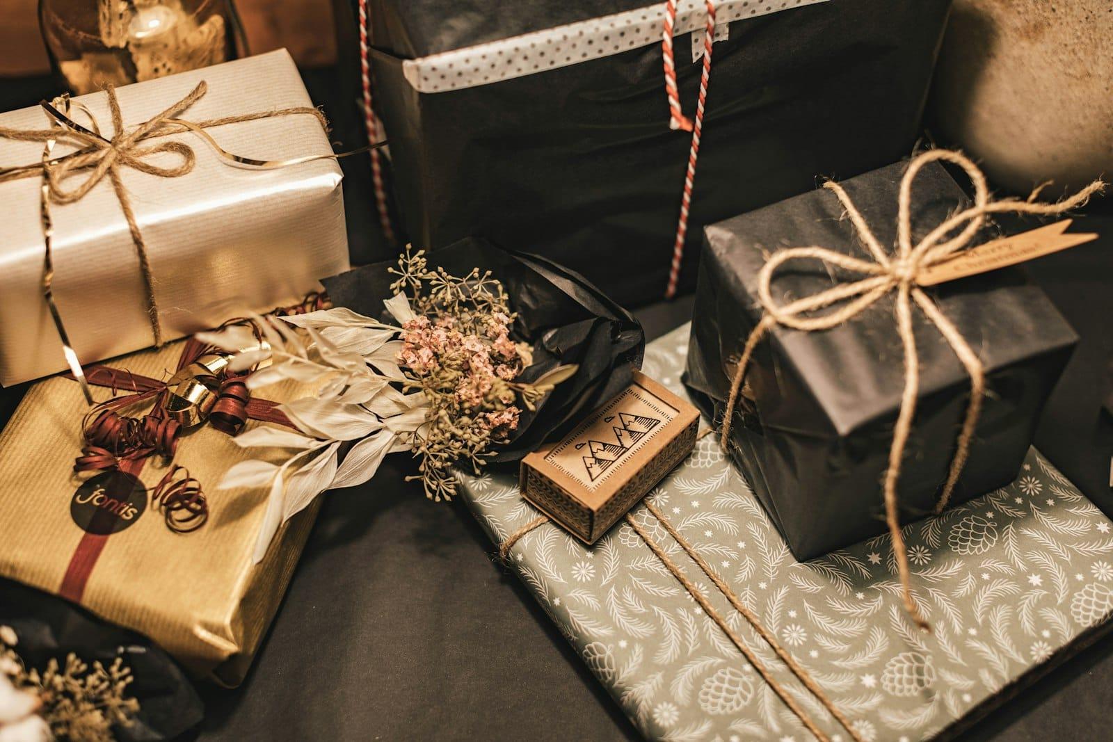 Christmas parcels in kraft, black and green paper tied with twine, dried flowers alongside