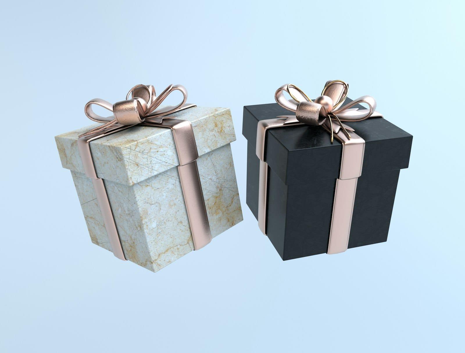 Two gift boxes, one marbled cream and one black, tied with rose-gold ribbon on pale blue