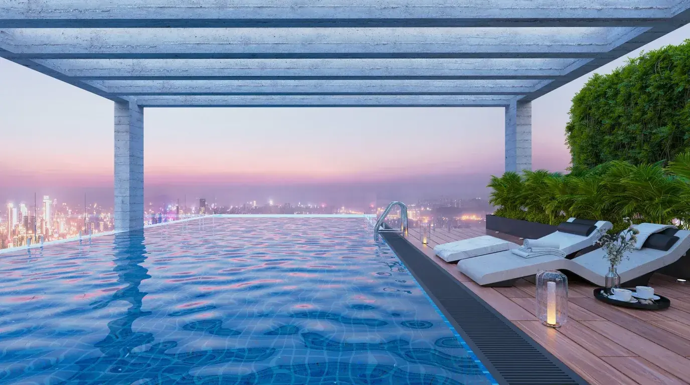 A rooftop infinity pool and loungers above a city skyline at dusk